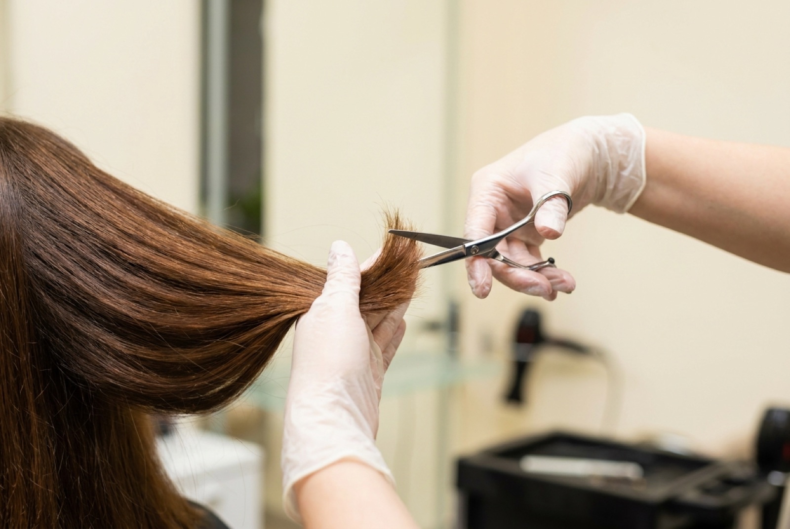 Haarschnitt Wien – Friseurin schneidet die Spitzen von langem braunem Haar mit der Schere